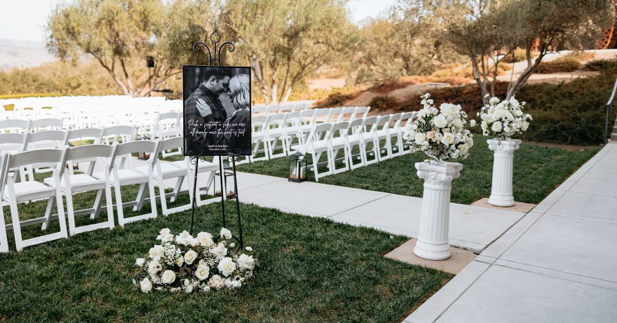 Outdoor wedding ceremony setup at a vineyard in Morgan Hill CA with white chairs, floral arrangements, and welcome signage at MOHI Ranch