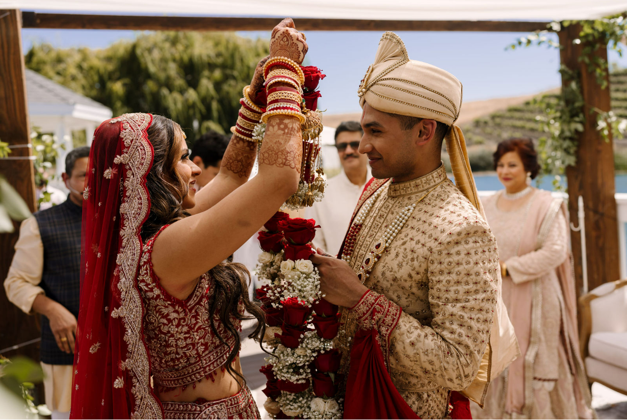 Couple exchanging ceremonial garlands during a culturally rich wedding ceremony coordinated through all inclusive wedding services at Léal Vineyards.