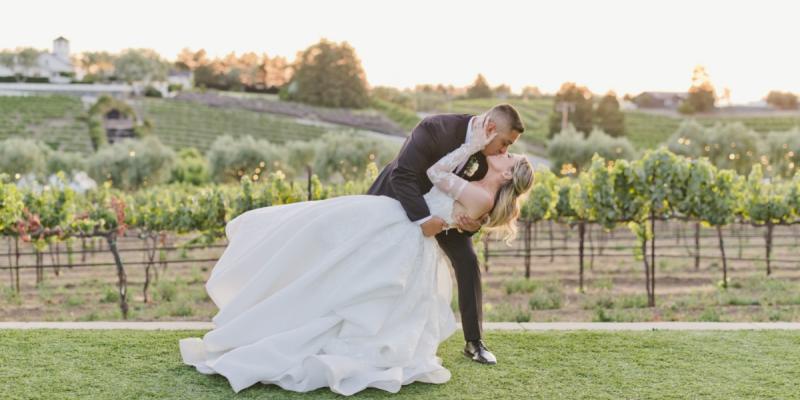 Bride and groom share a romantic dip and kiss at sunset during a vineyard wedding at Léal Vineyards in Hollister CA