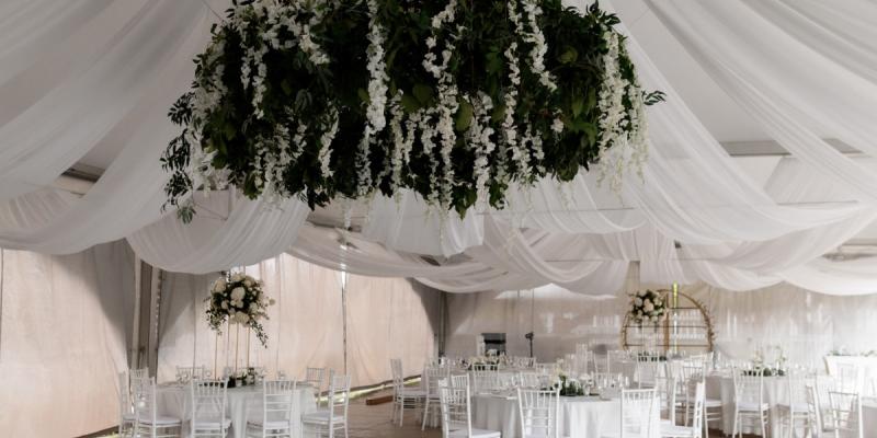 Elegant wedding reception setup with draped ceiling and chandelier at an event venue in California
