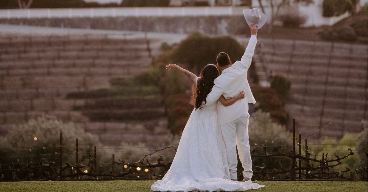 Bride and groom celebrating at sunset overlooking vineyard hills near Morgan Hill wedding venue
