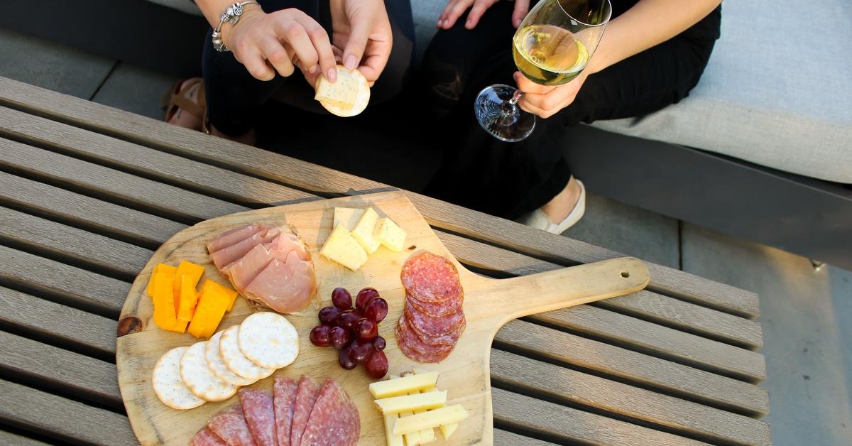 Charcuterie board and white wine enjoyed outdoors in California wine country near a vineyard wedding venue
