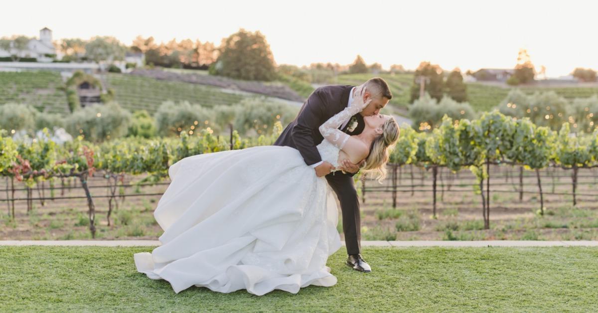 Bride and groom share a romantic dip and kiss at sunset during a vineyard wedding at Léal Vineyards in Hollister CA