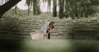 Bride and groom sharing a kiss under a tree at a vineyard wedding venue in Hollister CA